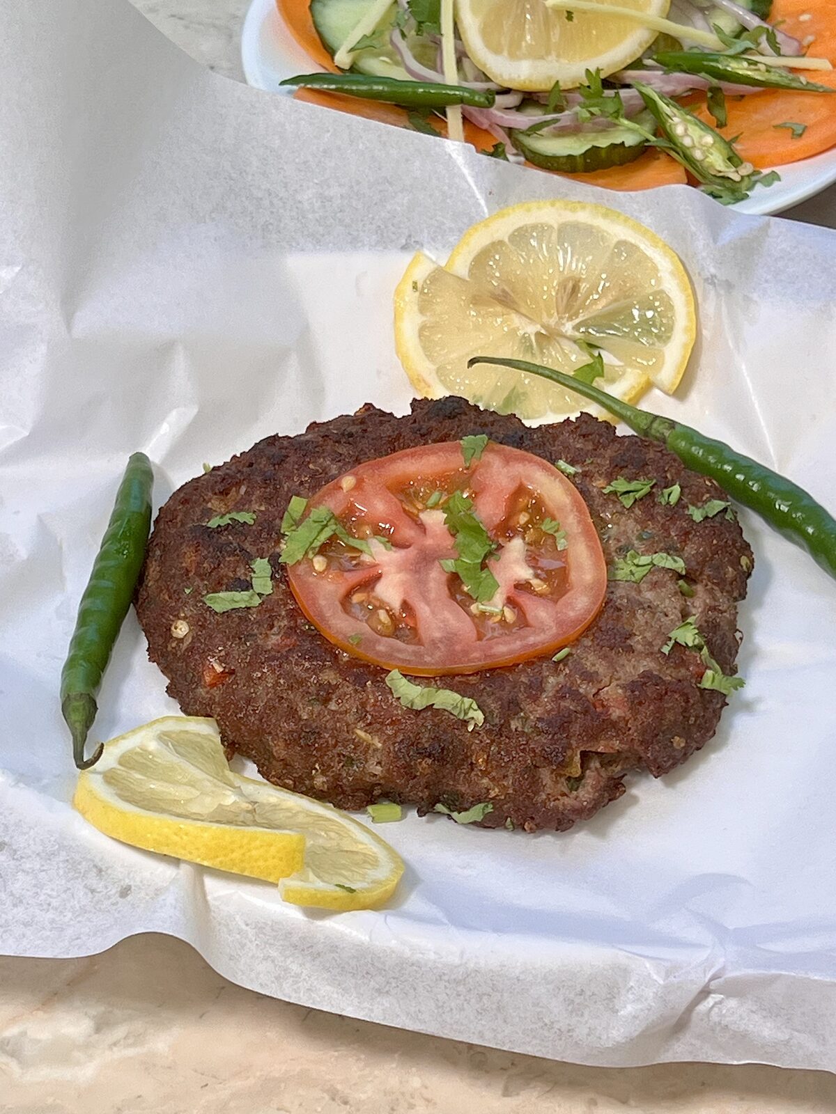 Chapli Kabab topped with tomato, coriander and green chilli